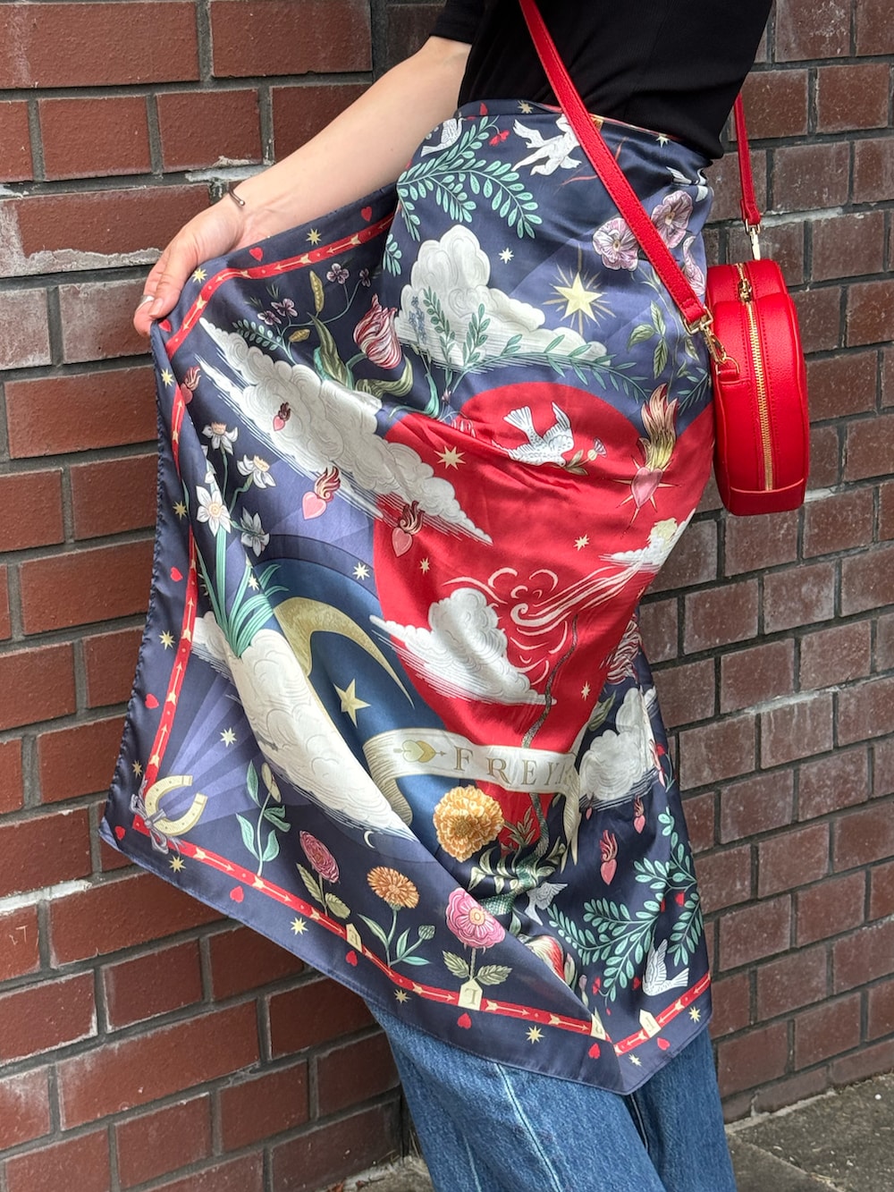 ブルー系のデニムパンツ、ブラック系のパンプス、レッド系のショルダーバッグを着用したレディースの夏コーディネートの3枚目の写真