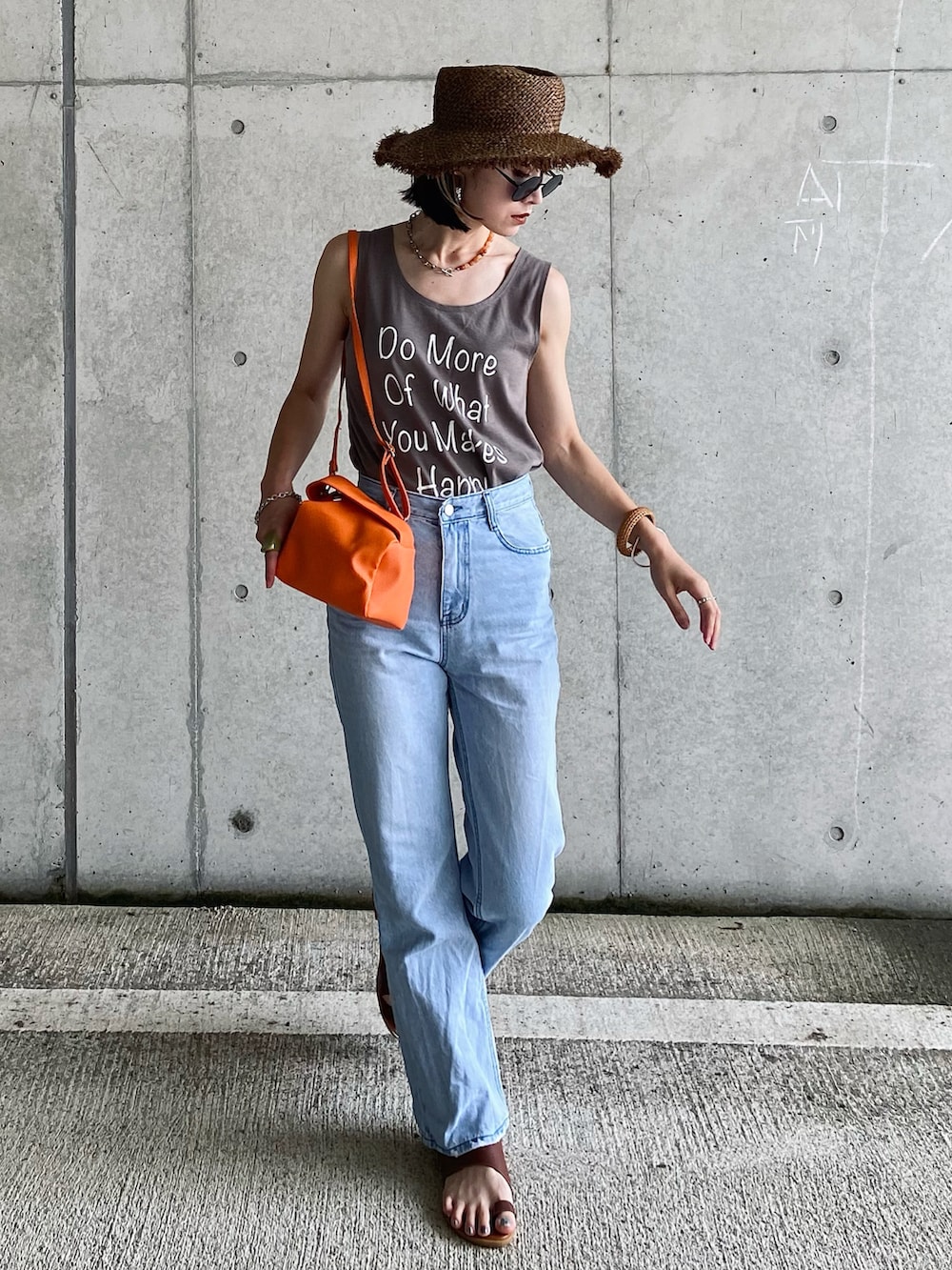 イエロー系のハンドバッグ、ホワイト系のタンクトップ、ブルー系のデニムパンツを着用したレディースの夏コーディネートの5枚目の写真