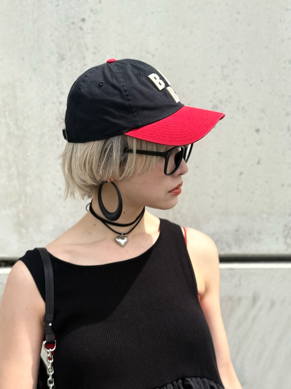 ブラック系のワンピース、レッド系のキャミソール、レッド系のスニーカーを着用したレディースの春コーディネートの5枚目の写真