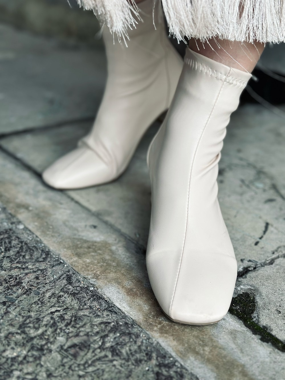 ホワイト系のブーツ、ブラック系のニット/セーター、ホワイト系のスカートを着用したレディースの冬コーディネートの2枚目の写真