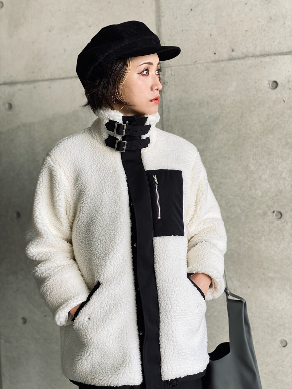 ホワイト系のブルゾン、ブラック系のワンピース、グレー系のショルダーバッグを着用したレディースの冬コーディネートの2枚目の写真