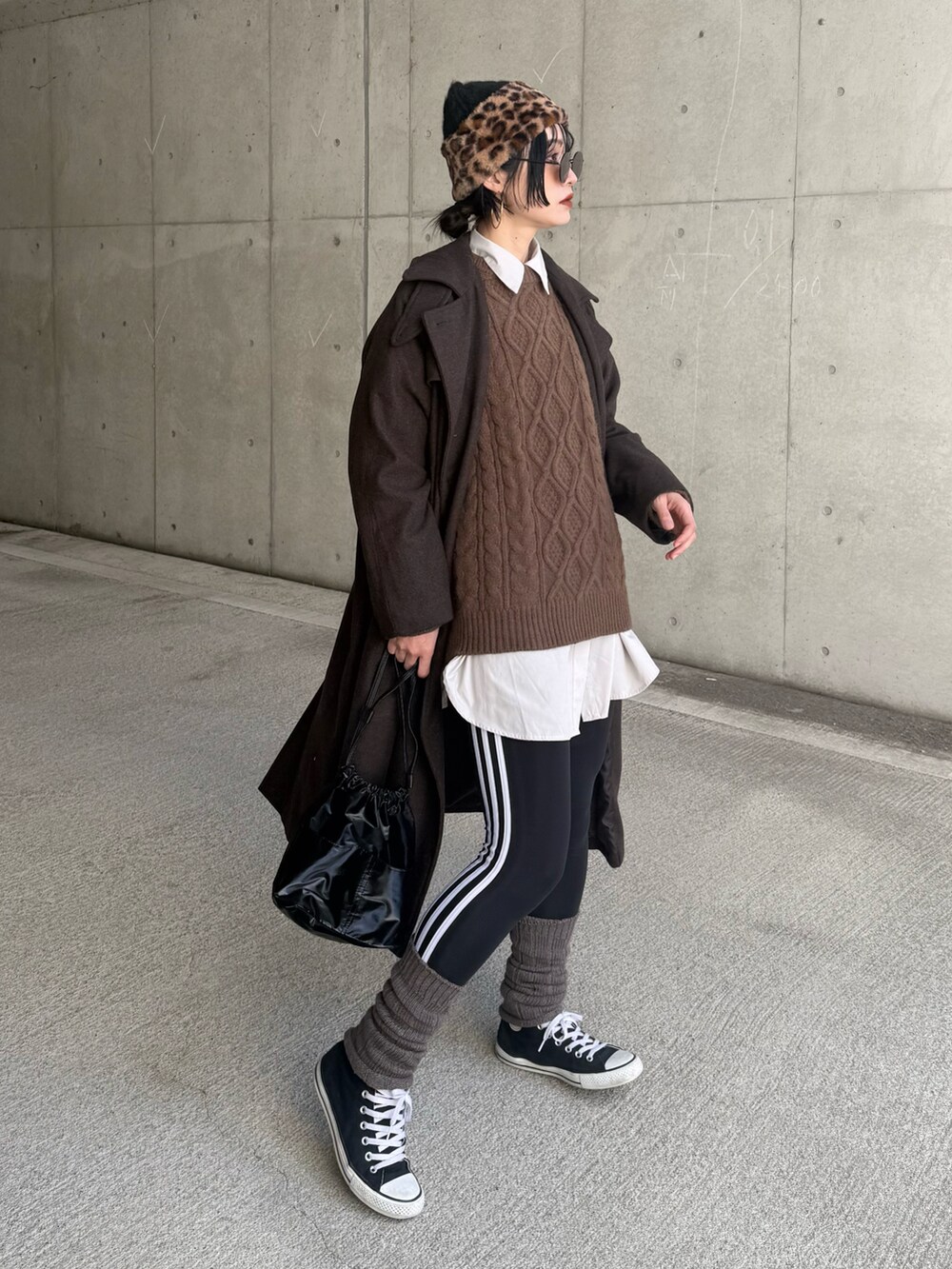 ブラウン系のステンカラーコート、ブラック系のハンドバッグ、ブラック系のその他パンツを着用したレディースの冬コーディネートの3枚目の写真