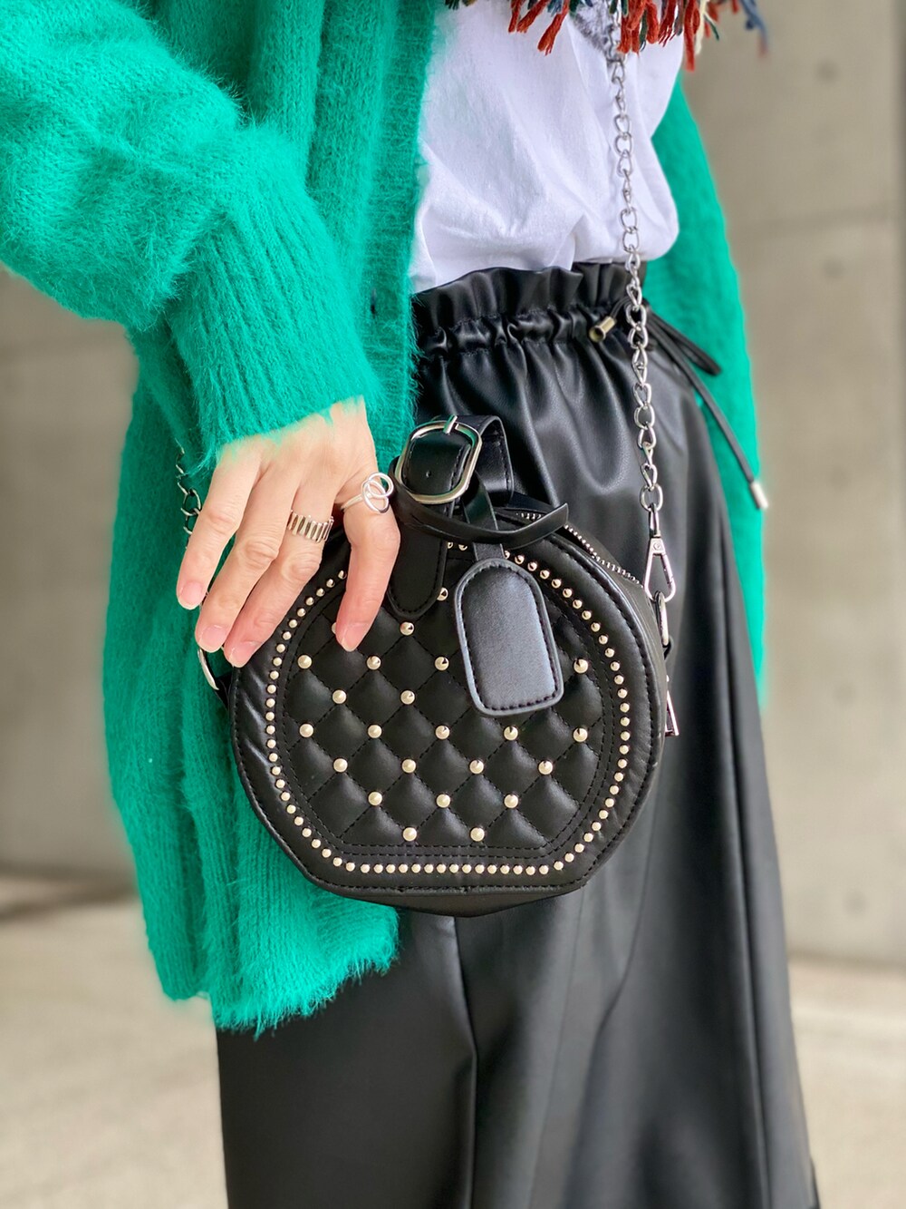 ブラック系のスカート、グリーン系のカーディガン/ボレロ、ブラック系のショルダーバッグを着用したレディースの冬コーディネートの3枚目の写真