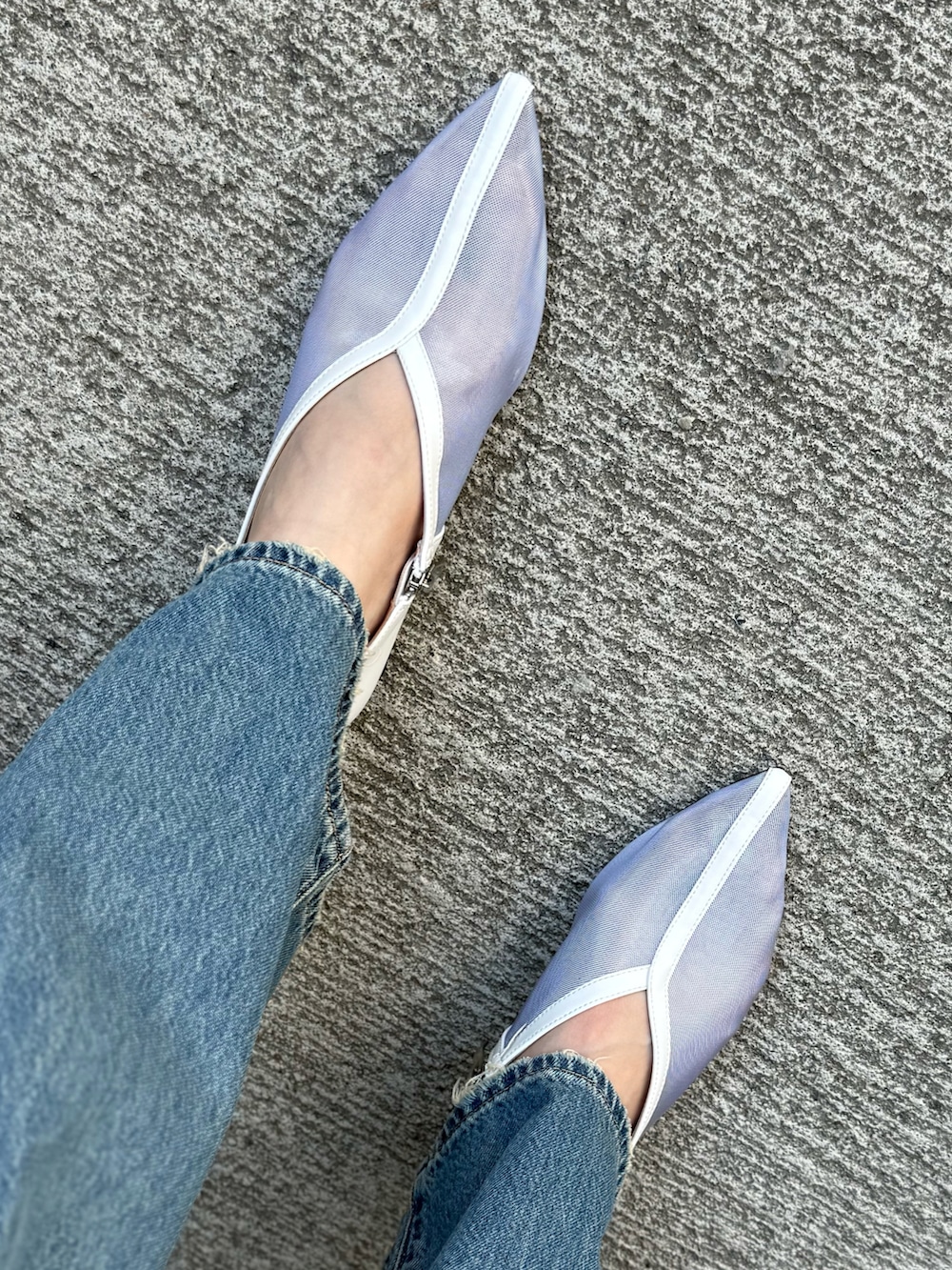 グレー系のベスト、ブラック系のトートバッグ、ブルー系のデニムパンツを着用したレディースの秋コーディネートの4枚目の写真