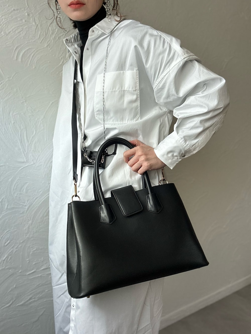 ホワイト系のシャツワンピース、ブラック系のショルダーバッグ、ブラック系のその他パンツを着用したレディースの冬コーディネートの3枚目の写真