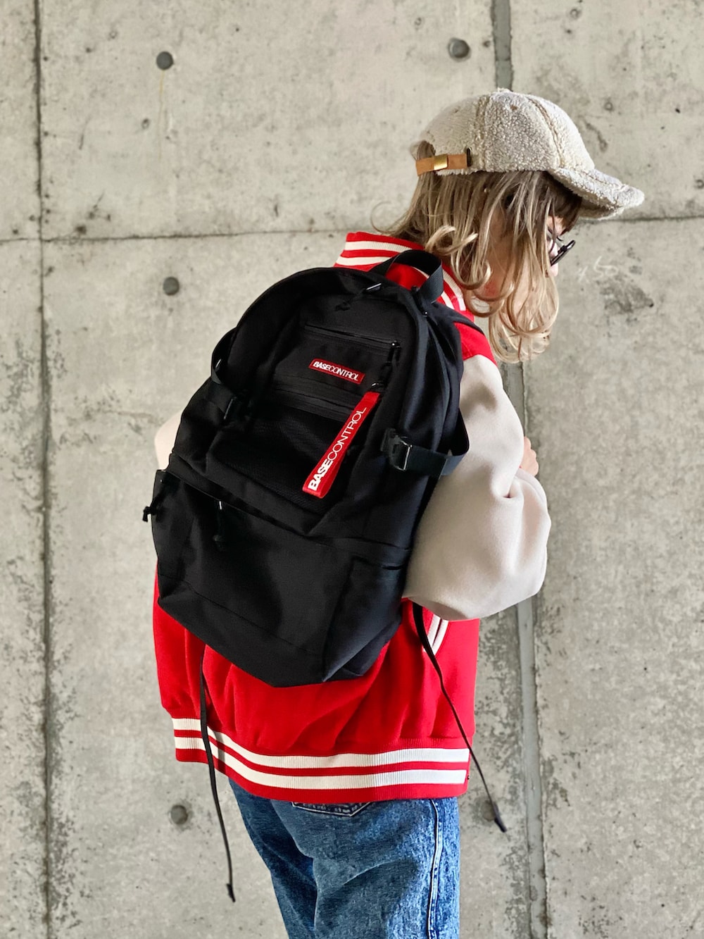 レッド系のスタジャン、ベージュ系のスウェット、ブルー系のデニムパンツを着用したレディースの冬コーディネートの4枚目の写真