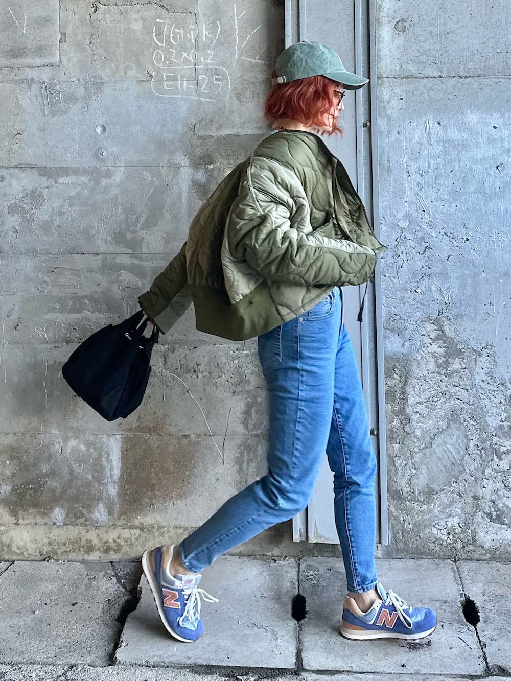 ホワイト系のニット/セーター、ブルー系のデニムパンツ、グリーン系のミリタリージャケットを着用したレディースの冬コーディネートの4枚目の写真