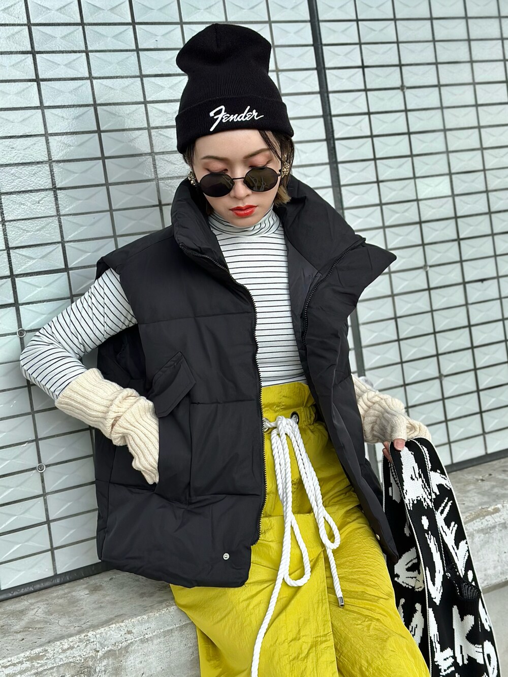 ブラック系のダウンベスト、イエロー系のスカート、ホワイト系のスニーカーを着用したレディースの冬コーディネートの2枚目の写真