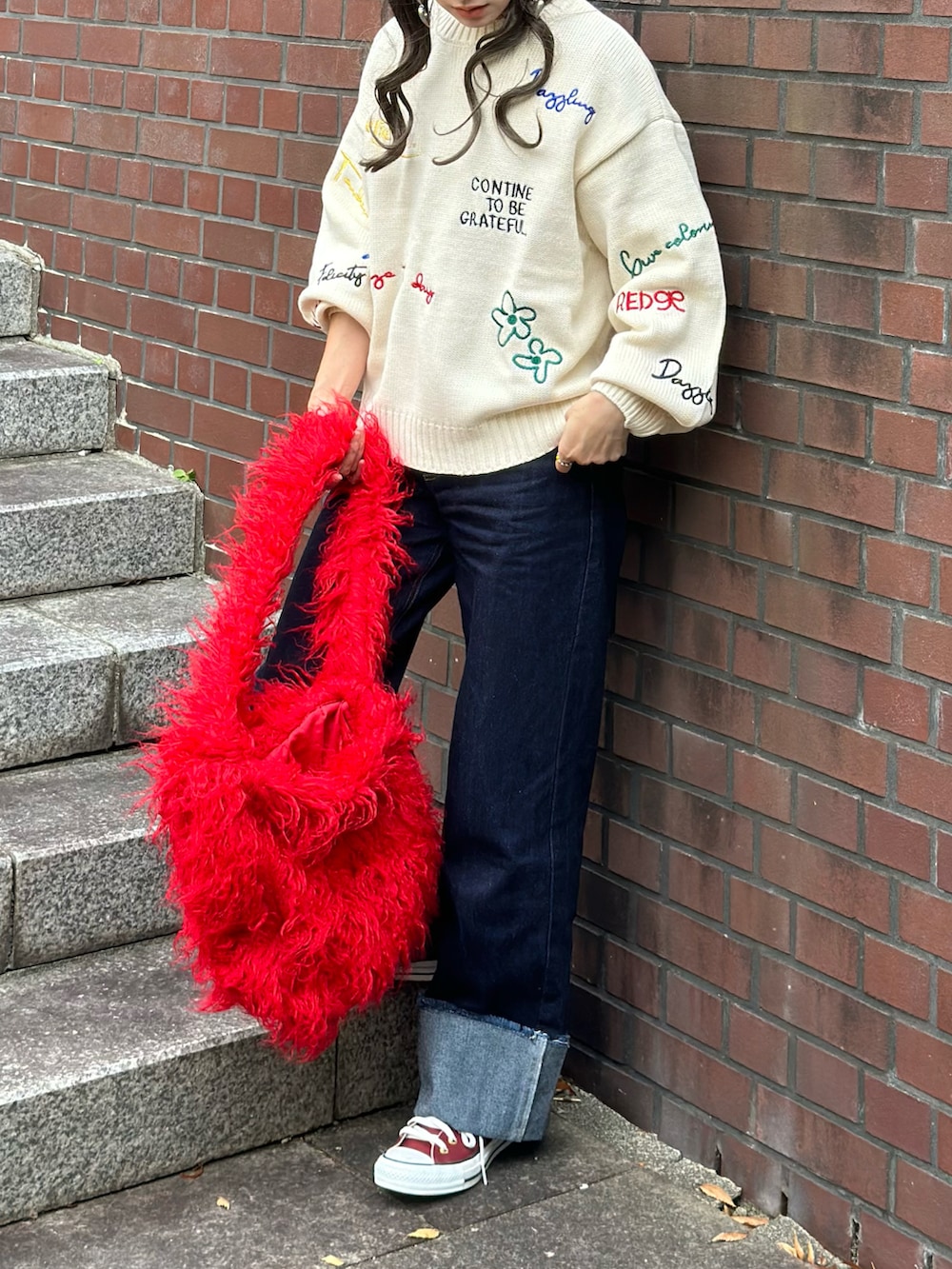 ホワイト系のニット/セーター、ブルー系のデニムパンツ、レッド系のトートバッグを着用したレディースの秋コーディネートの5枚目の写真
