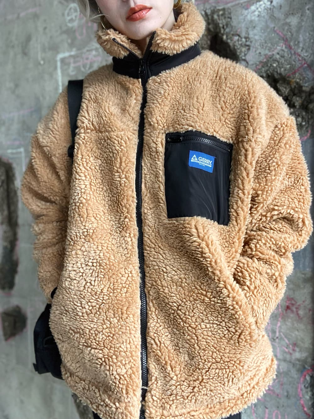 ベージュ系のブルゾン、ブラック系のショルダーバッグ、ブラック系のデニムパンツを着用したレディースの冬コーディネートの2枚目の写真