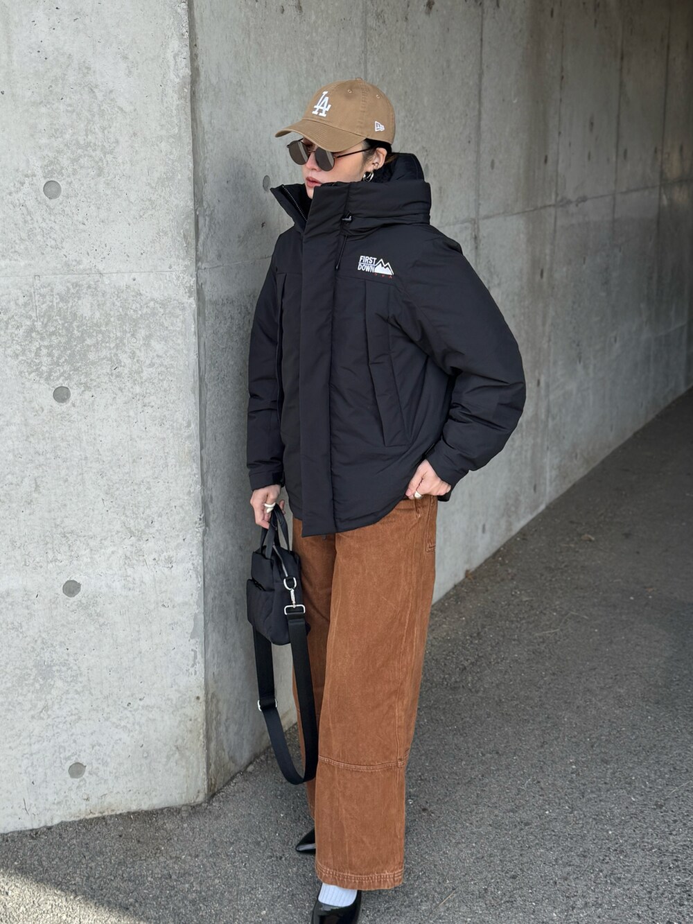 ブラック系のダウンジャケット/コート、ブラウン系のデニムパンツ、ブラック系のパンプスを着用したレディースの冬コーディネートの5枚目の写真