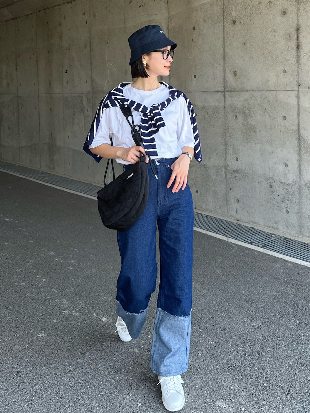 ブルー系のアンサンブル、ブラック系のショルダーバッグ、ブルー系のデニムパンツを着用したレディースの夏コーディネートの4枚目の写真