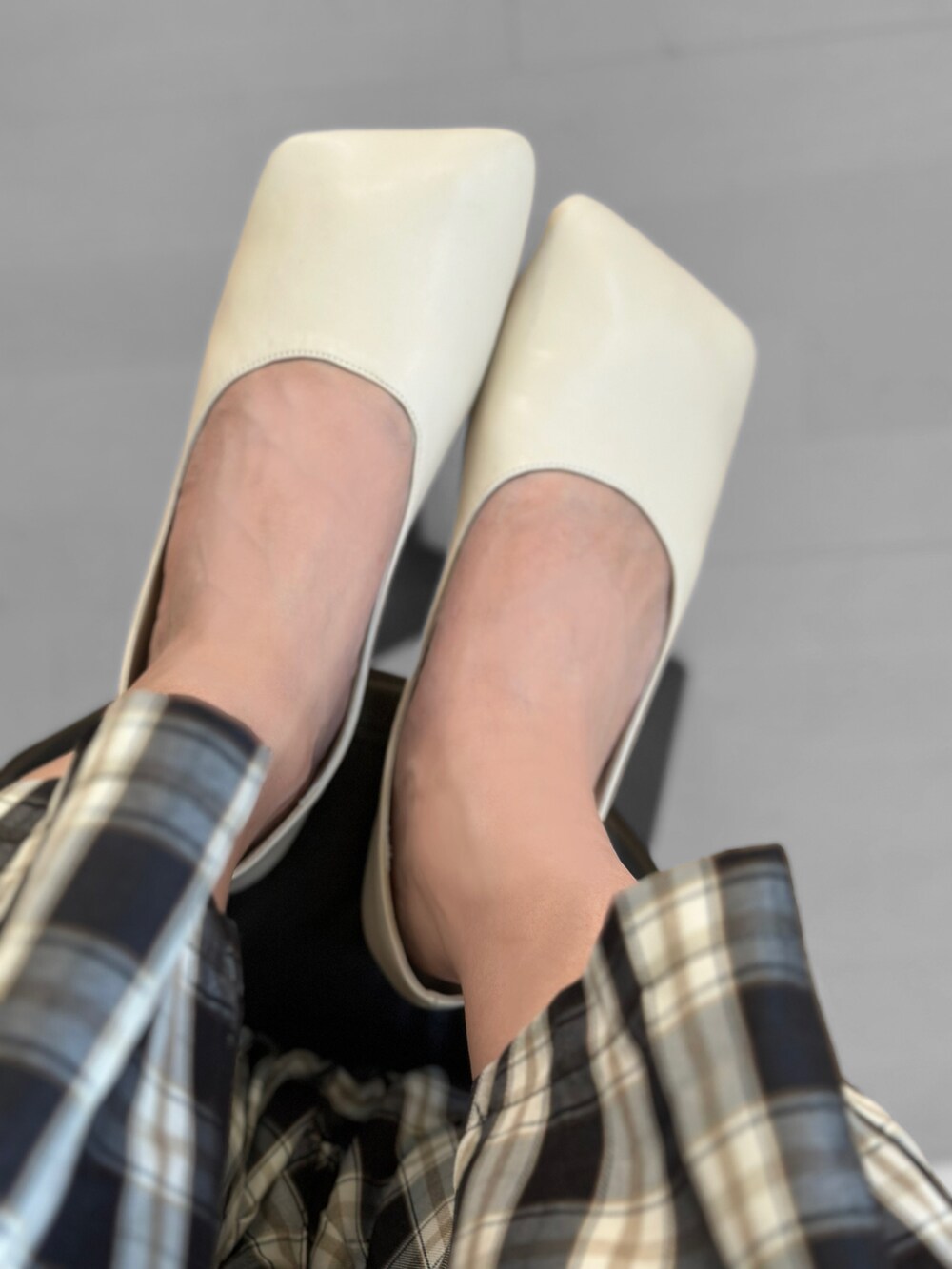 ホワイト系のトートバッグ、ホワイト系のパンプス、ブラック系のスラックスを着用したレディースの秋コーディネートの4枚目の写真