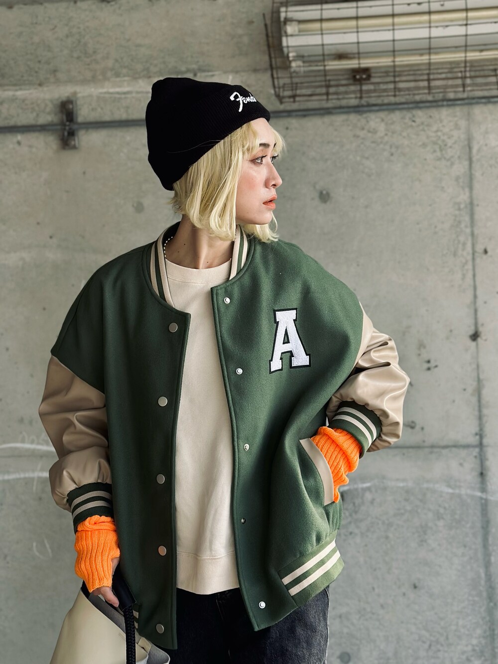 ホワイト系のスウェット、グリーン系のスタジャン、ホワイト系のハンドバッグを着用したレディースの冬コーディネートの2枚目の写真