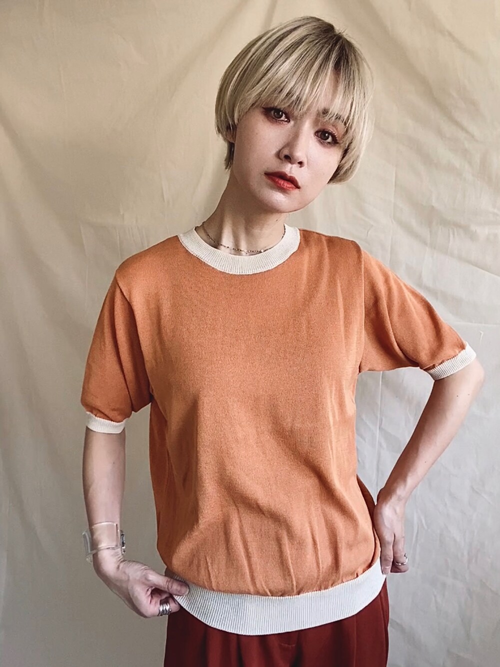 オレンジ系のニット/セーター、ホワイト系のサンダル、ホワイト系のサロペット/オーバーオールを着用したレディースの春コーディネートの4枚目の写真