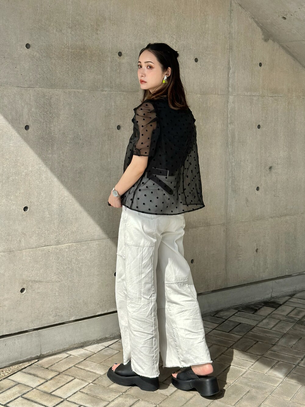 ブラック系のチューブトップ、ブルー系のデニムパンツ、ブラック系のサンダルを着用したレディースの春コーディネートの3枚目の写真
