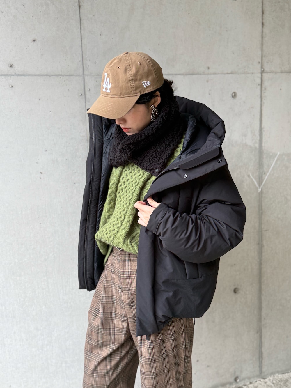 ブラック系のダウンジャケット/コート、ブラウン系のサロペット/オーバーオール、グリーン系のニット/セーターを着用したレディースの冬コーディネートの2枚目の写真