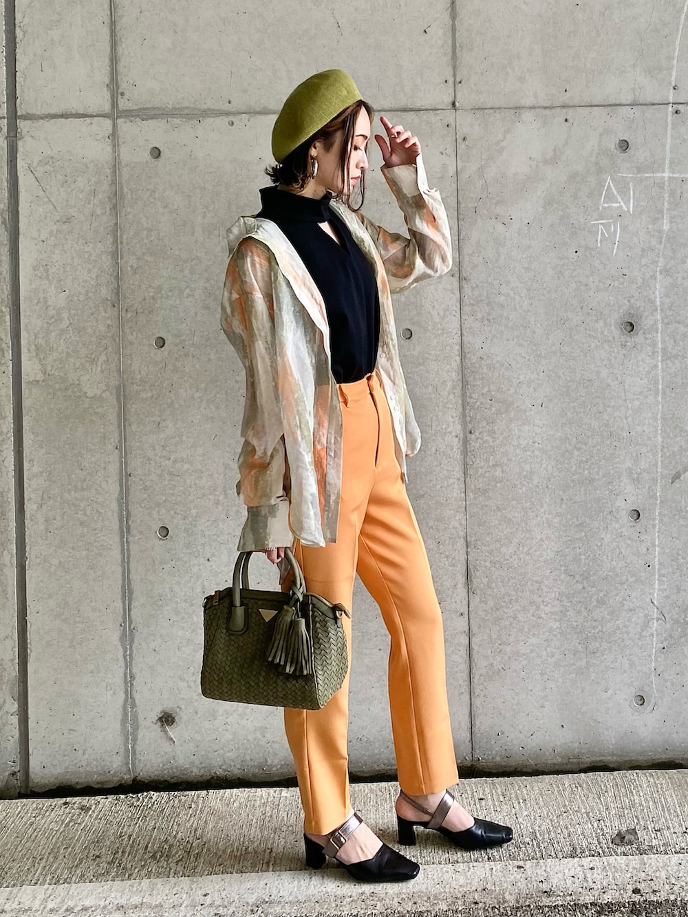 ブラック系のTシャツ/カットソー、オレンジ系のスラックス、グリーン系のハンドバッグを着用したレディースの春コーディネートの5枚目の写真