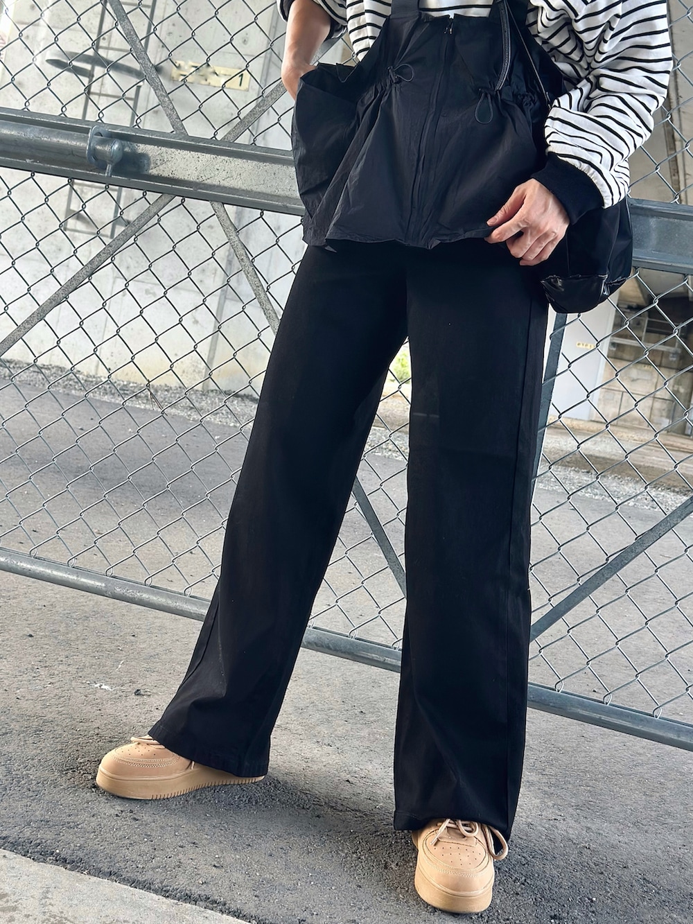 ブラック系のデニムパンツ、ベージュ系のスニーカー、ブラック系のTシャツ/カットソーを着用したレディースの秋コーディネートの5枚目の写真