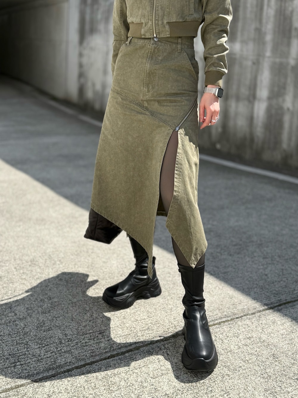 グリーン系のブルゾン、グリーン系のスカート、ブラック系のハンドバッグを着用したレディースの春コーディネートの3枚目の写真