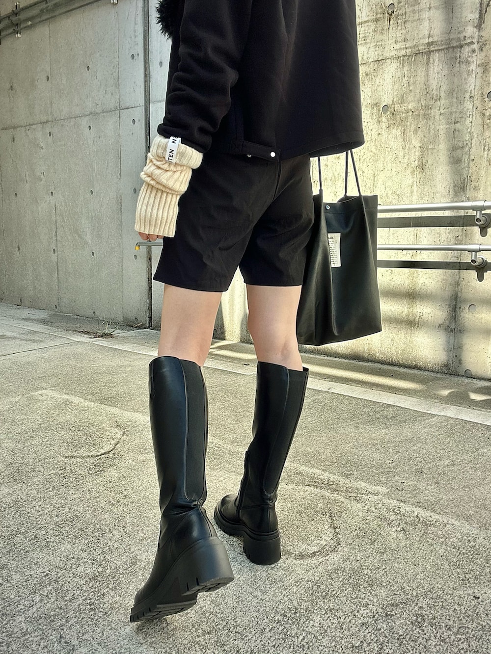 ブラック系のカーディガン/ボレロ、ブラック系のトートバッグ、ブラック系のブーツを着用したレディースの秋コーディネートの3枚目の写真