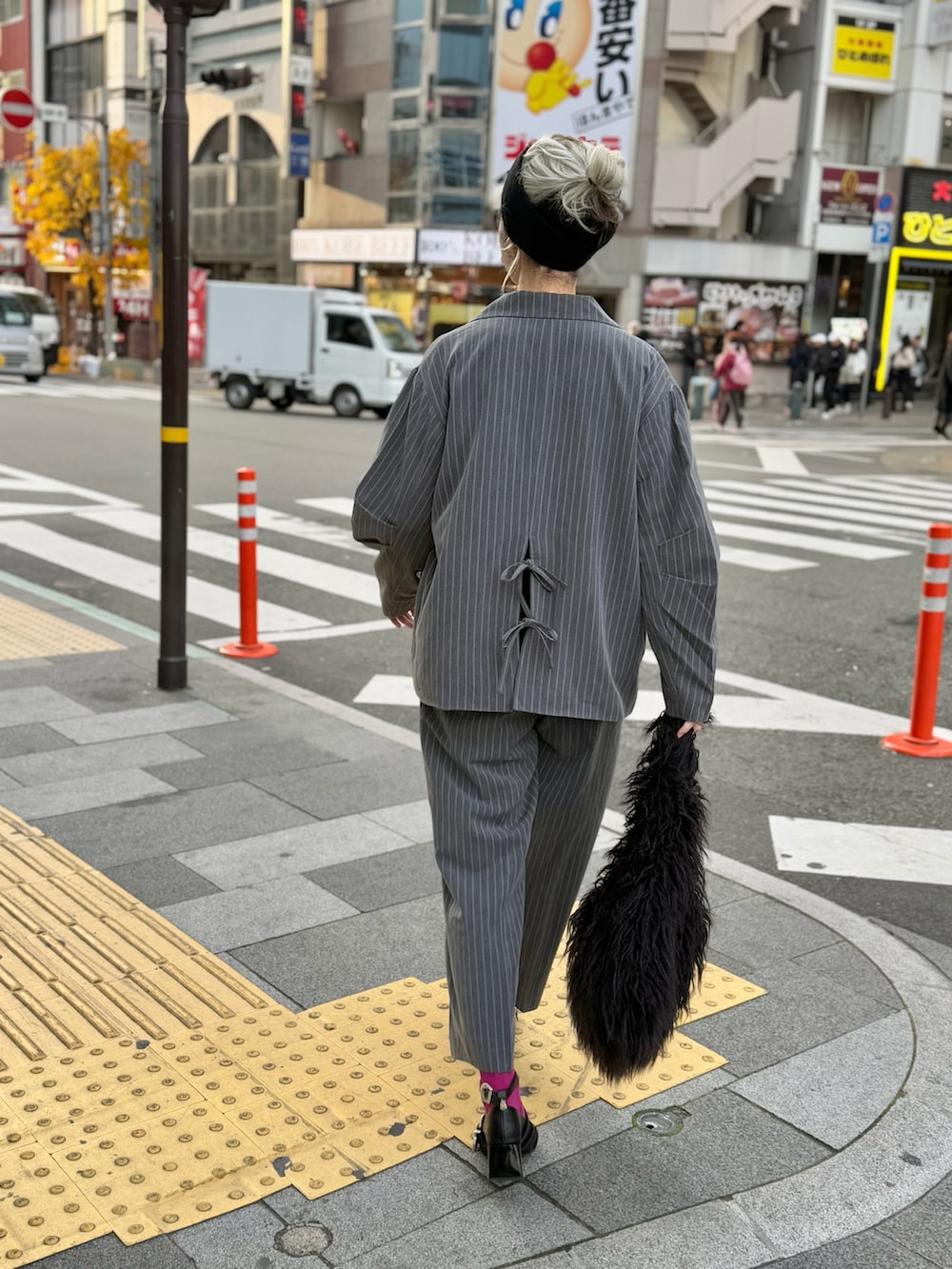 グレー系のセットアップ、ブラック系のニット/セーター、ブラック系のトートバッグを着用したレディースの冬コーディネートの3枚目の写真