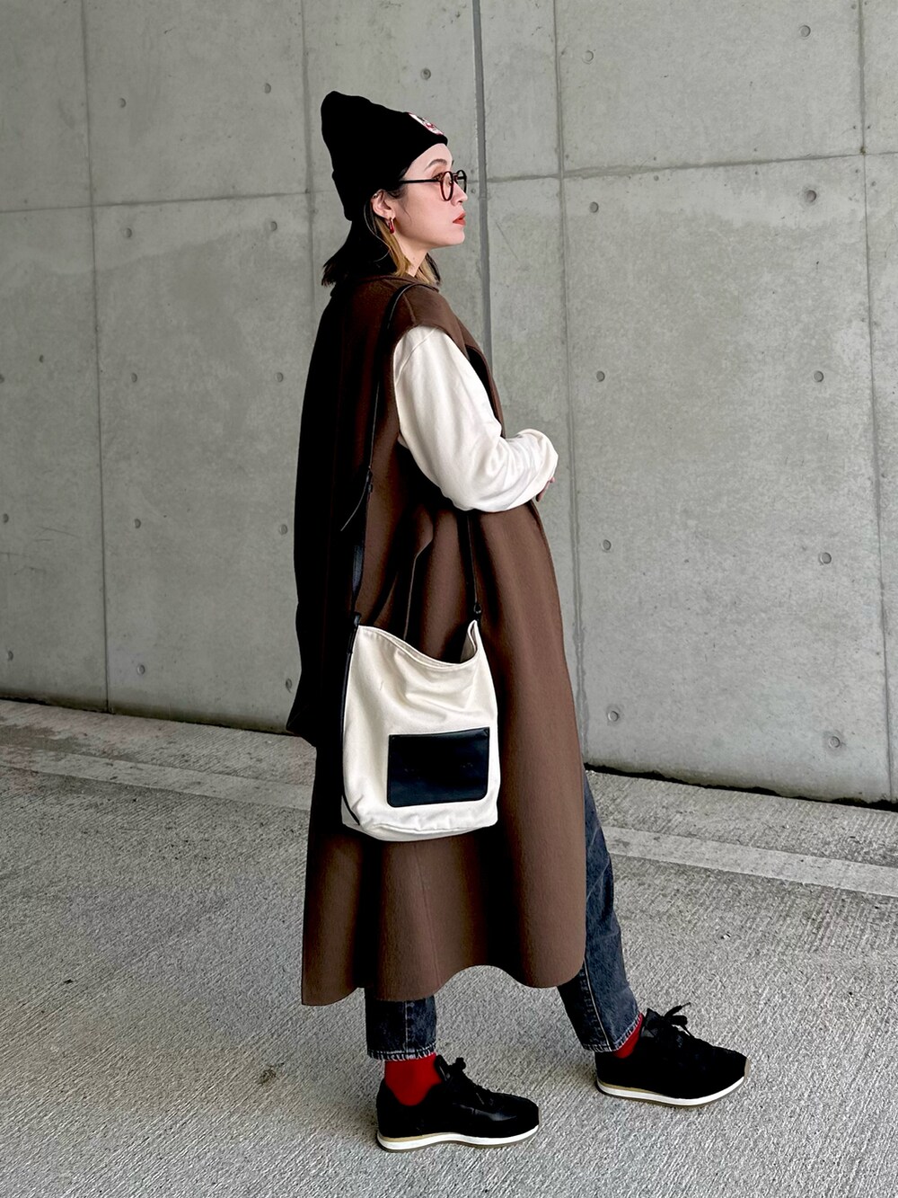 ホワイト系のスウェット、ブラウン系のチェスターコート、ブラック系のスニーカーを着用したレディースの秋コーディネートの5枚目の写真