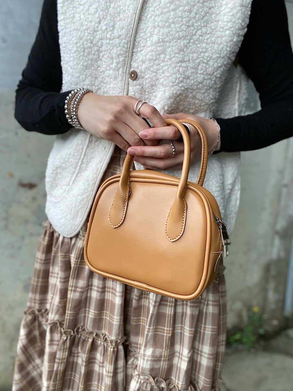 ブラウン系のスカート、ブラック系のTシャツ/カットソー、ブラウン系のブーツを着用したレディースの春コーディネートの5枚目の写真