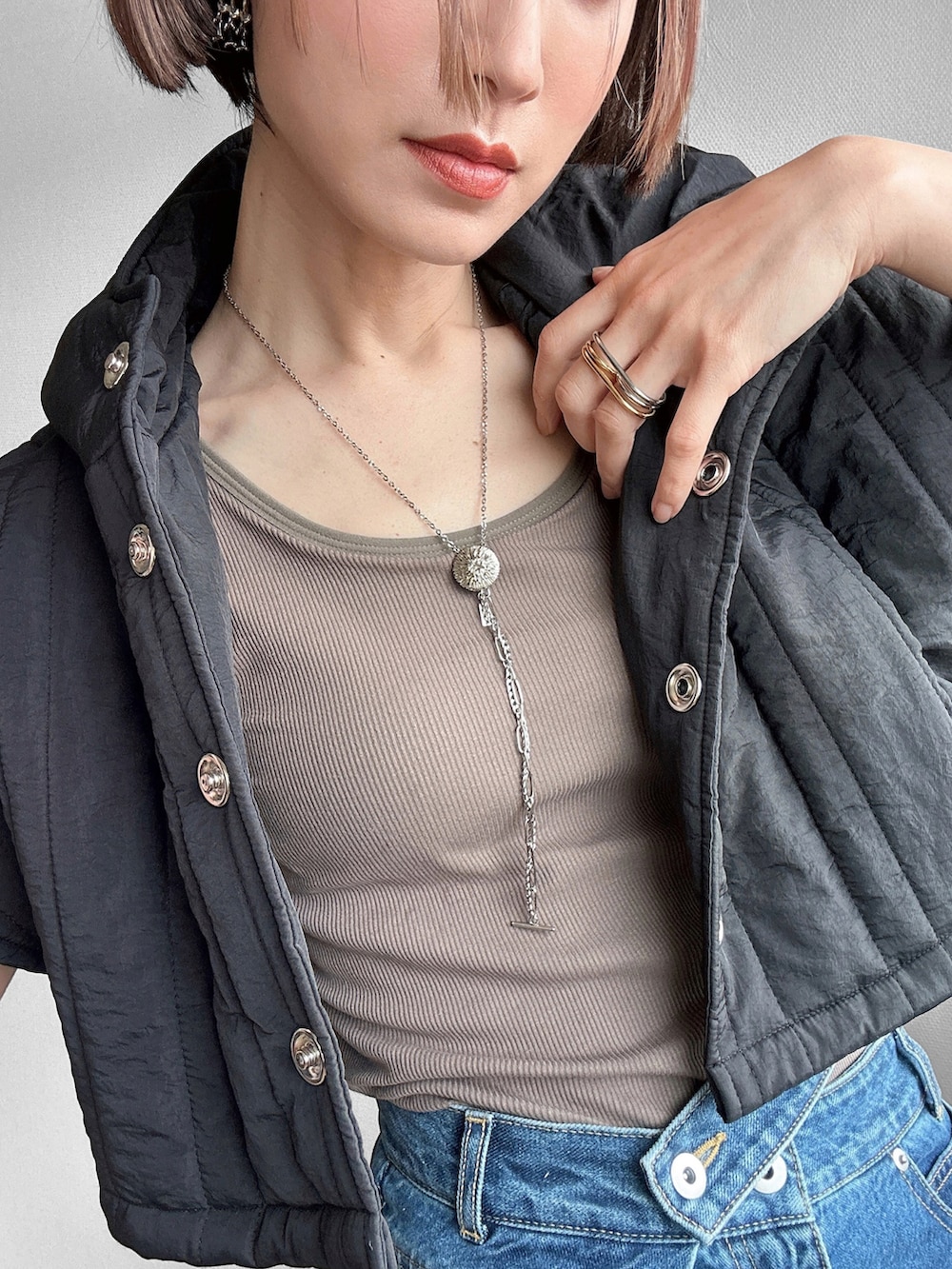 グリーン系のタンクトップ、ブルー系のデニムパンツ、ブラック系のその他アウターを着用したレディースの春コーディネートの3枚目の写真