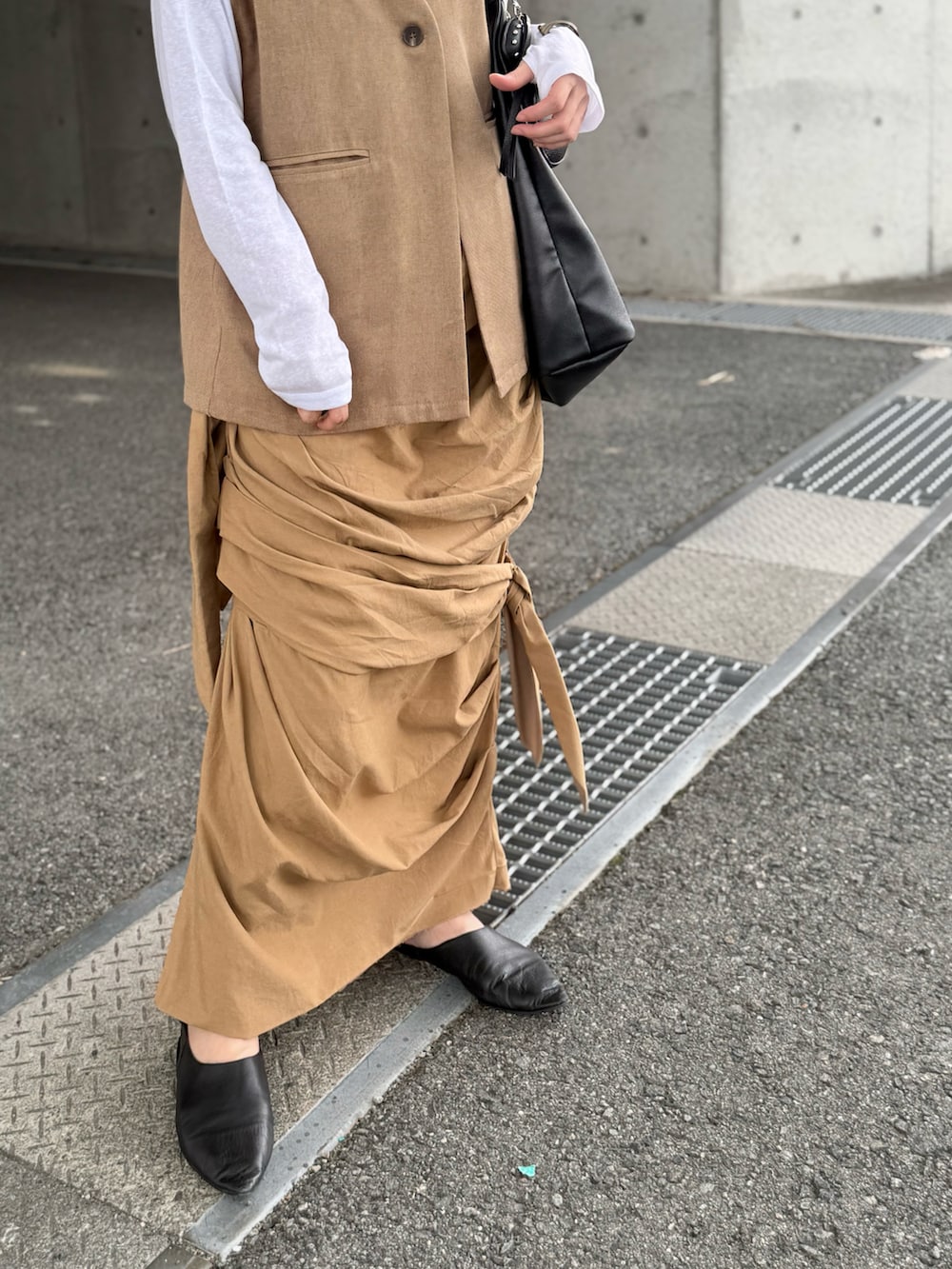 グリーン系のベスト、ホワイト系のTシャツ/カットソー、ベージュ系のスカートを着用したレディースの秋コーディネートの3枚目の写真