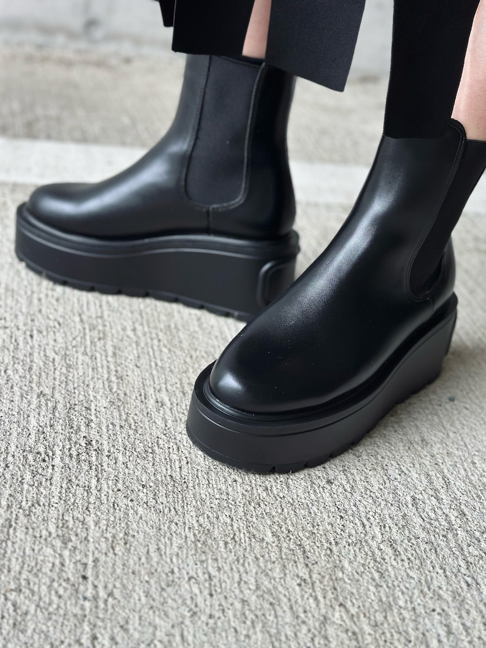 ブラック系のブーツ、ブラック系のカーディガン/ボレロ、シルバー系のハンドバッグを着用したレディースの秋コーディネートの2枚目の写真