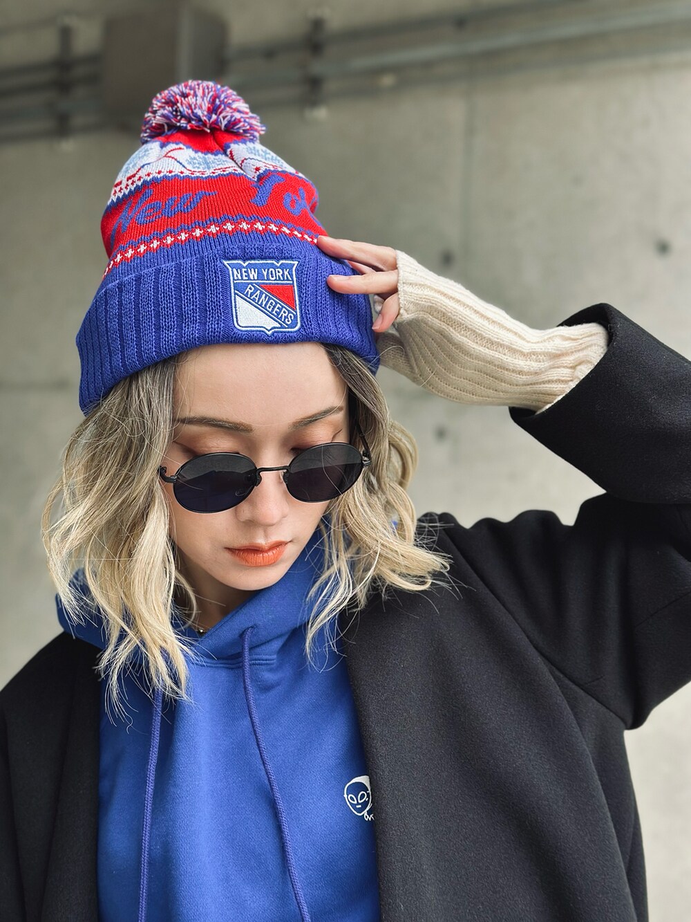 ブラック系のノーカラーコート、ブルー系のパーカー、ホワイト系のその他パンツを着用したレディースの冬コーディネートの2枚目の写真