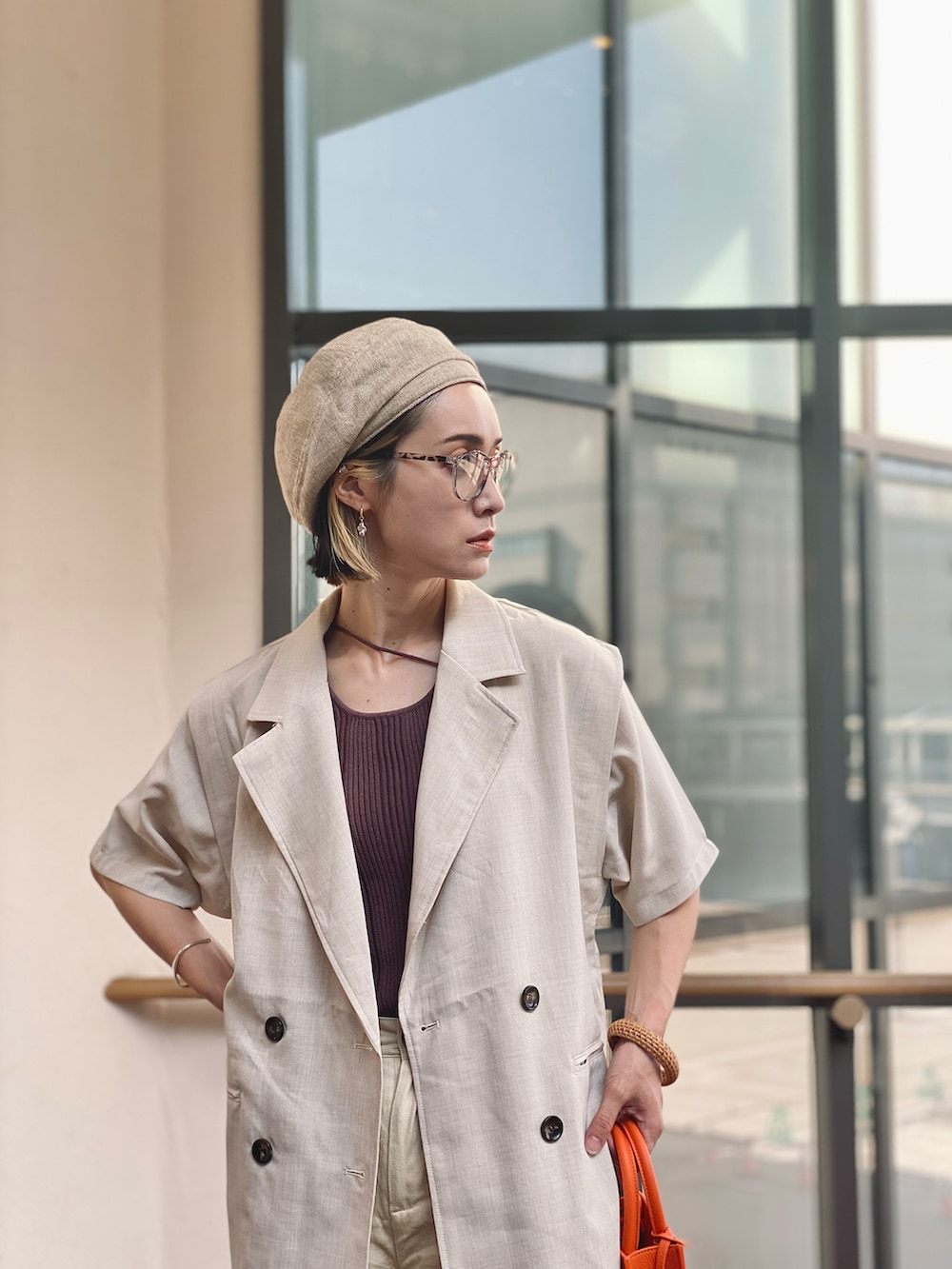 ホワイト系のベスト、ブラウン系のタンクトップ、オレンジ系のトートバッグを着用したレディースの夏コーディネートの5枚目の写真