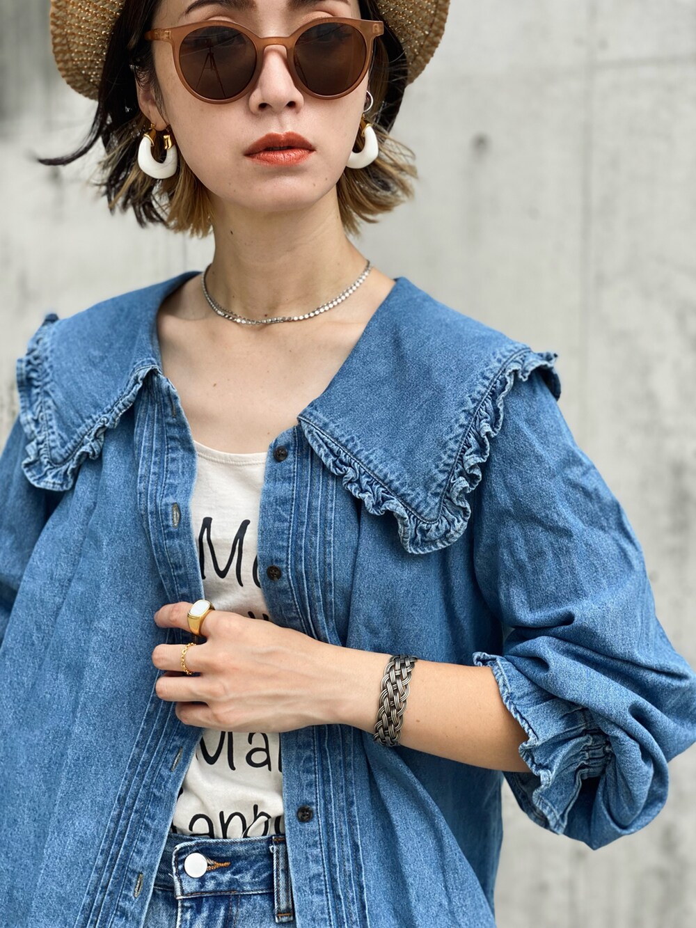 ブラック系のトートバッグ、ブルー系のシャツ/ブラウス、ホワイト系のブーツを着用したレディースの夏コーディネートの4枚目の写真