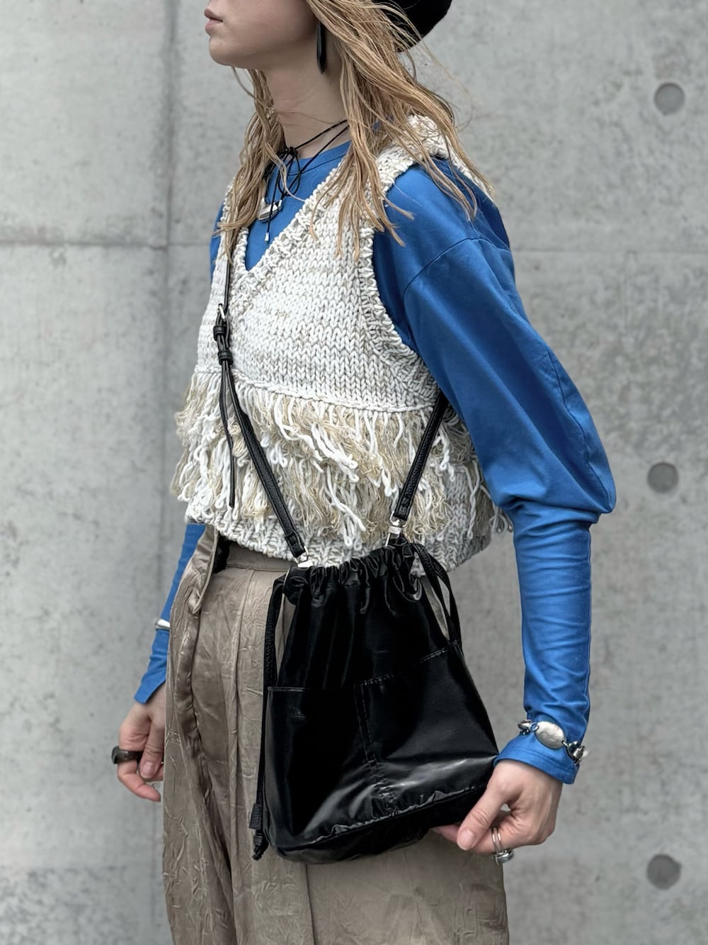 ブラック系のハンドバッグ、ブルー系のTシャツ/カットソー、ホワイト系のベストを着用したレディースの春コーディネートの5枚目の写真