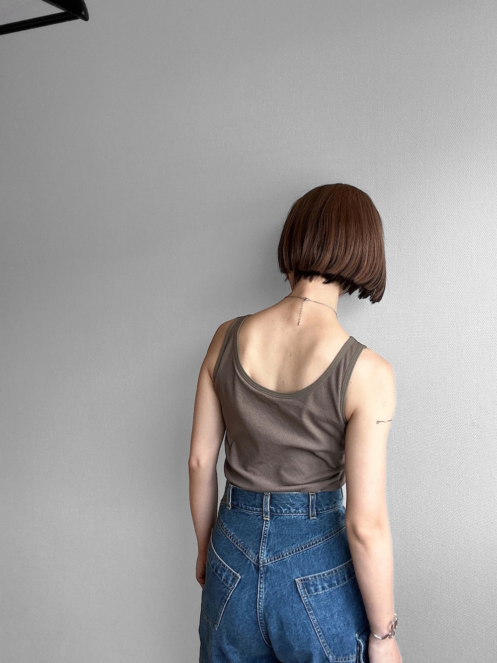 グリーン系のタンクトップ、ブルー系のデニムパンツ、ブラック系のその他アウターを着用したレディースの春コーディネートの4枚目の写真