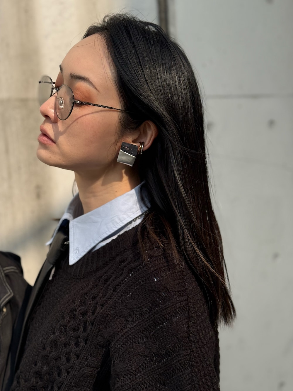 ブラック系のニット/セーター、ブルー系のデニムパンツ、その他のネクタイを着用したレディースの冬コーディネートの5枚目の写真