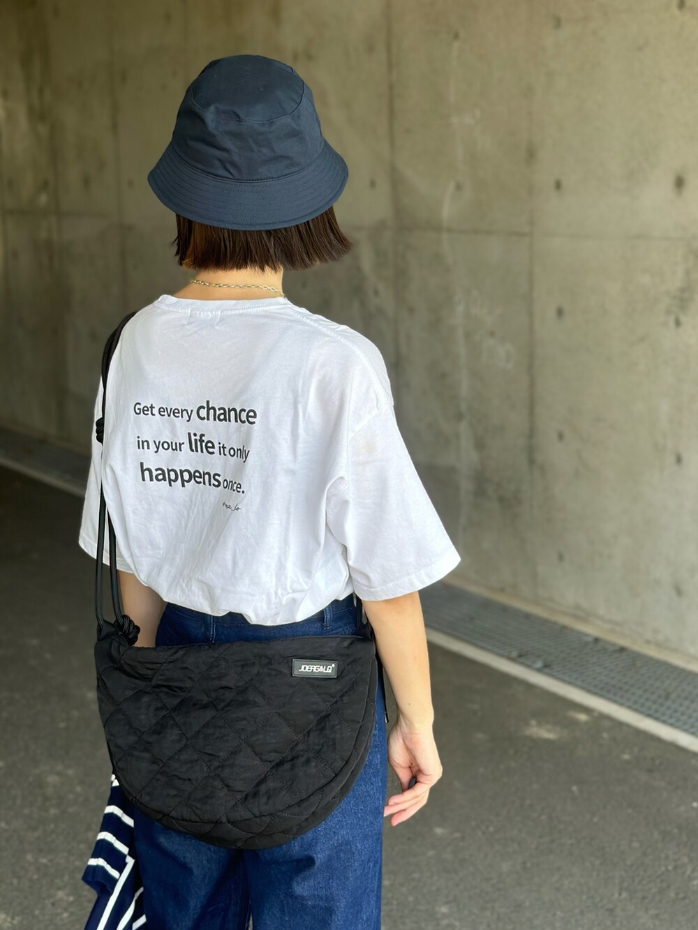 ブルー系のアンサンブル、ブラック系のショルダーバッグ、ブルー系のデニムパンツを着用したレディースの夏コーディネートの5枚目の写真