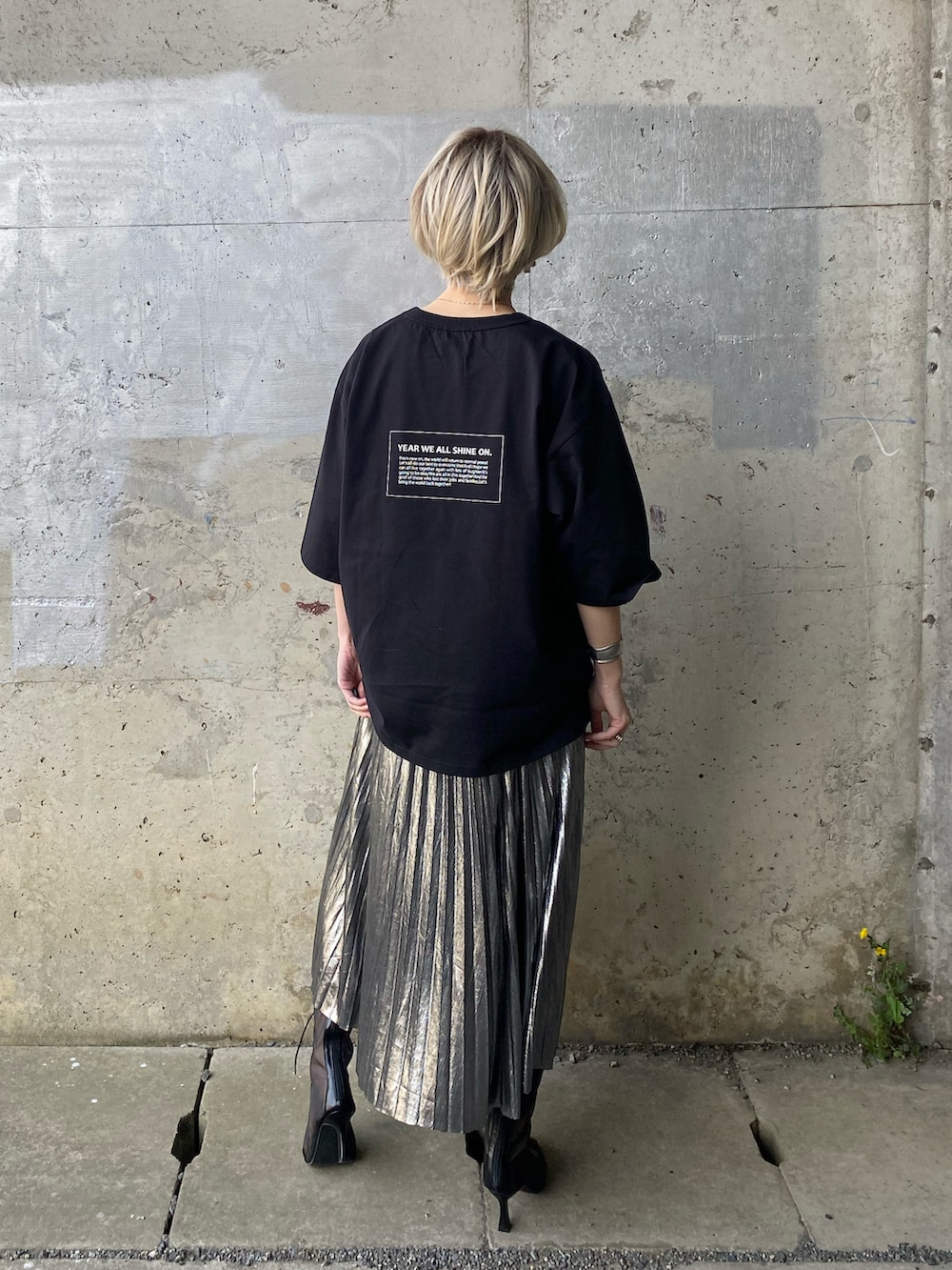 シルバー系のスカート、ブラック系のブーツ、ブラック系のTシャツ/カットソーを着用したレディースの春コーディネートの5枚目の写真