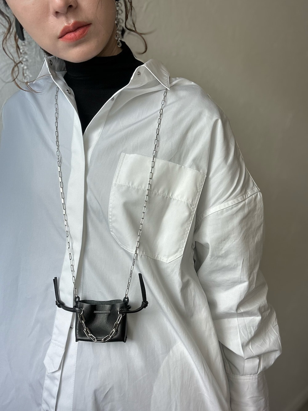 ホワイト系のシャツワンピース、ブラック系のショルダーバッグ、ブラック系のその他パンツを着用したレディースの冬コーディネートの5枚目の写真