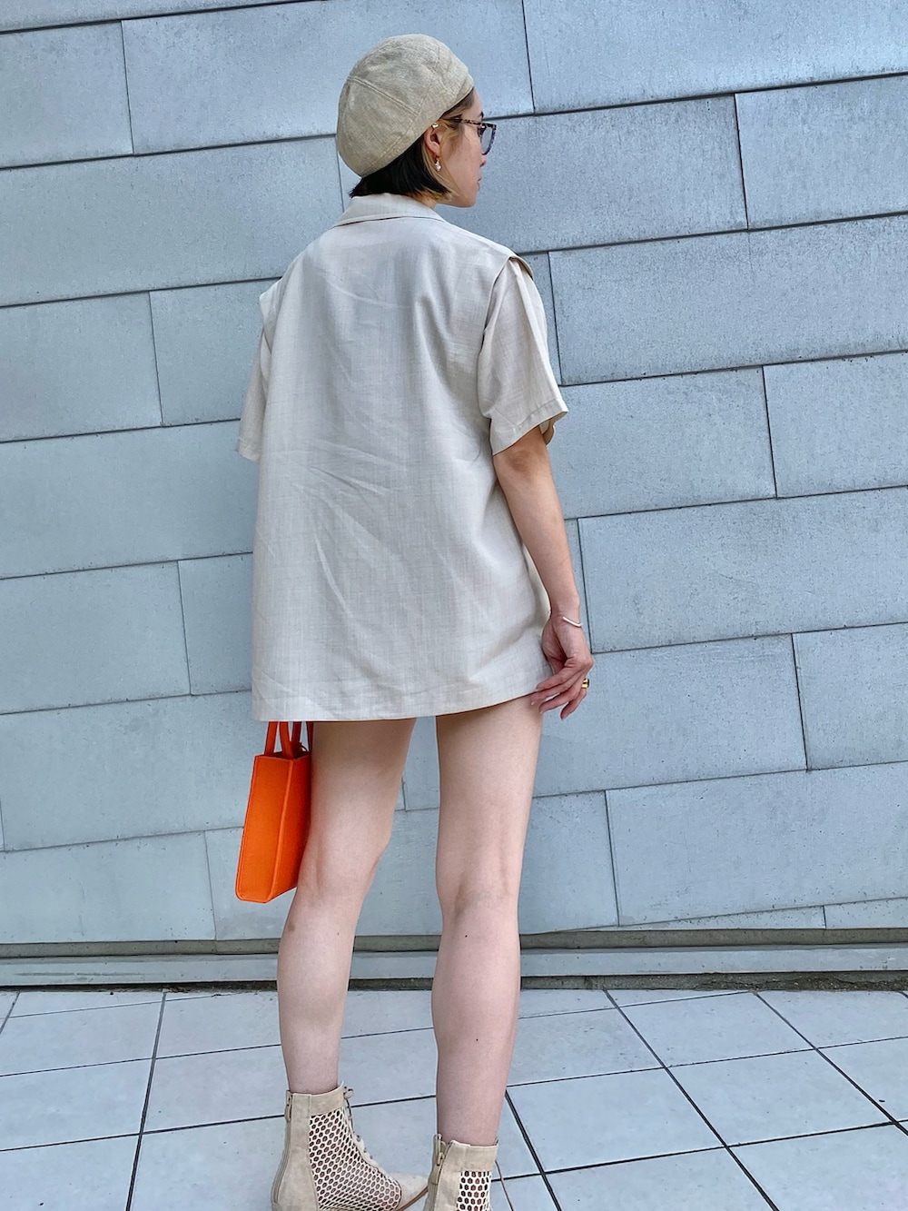 ホワイト系のベスト、ブラウン系のタンクトップ、オレンジ系のトートバッグを着用したレディースの夏コーディネートの4枚目の写真