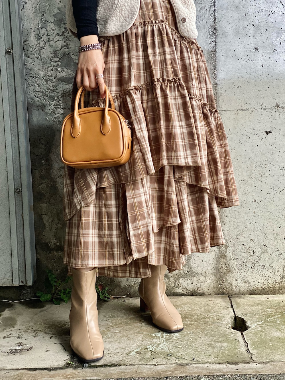 ブラウン系のスカート、ブラック系のTシャツ/カットソー、ブラウン系のブーツを着用したレディースの春コーディネートの3枚目の写真