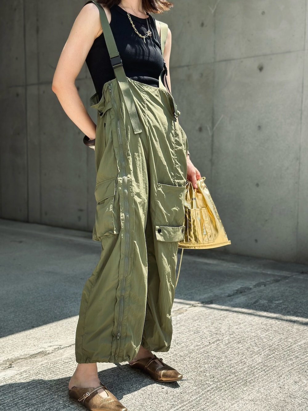 グリーン系のカーゴパンツ、ゴールド系のパンプス、ゴールド系のショルダーバッグを着用したレディースの夏コーディネートの2枚目の写真