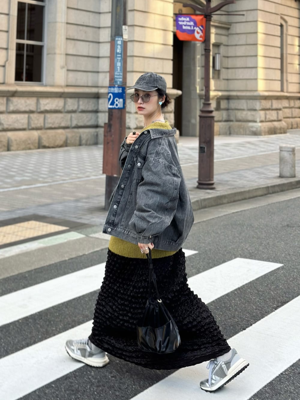 イエロー系のニット/セーター、ブラック系のハンドバッグ、グレー系のスニーカーを着用したレディースの秋コーディネートの3枚目の写真