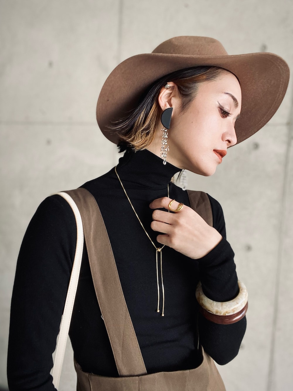 ブラウン系のサロペット/オーバーオール、ブラック系のTシャツ/カットソー、ブラック系のブーツを着用したレディースの冬コーディネートの4枚目の写真