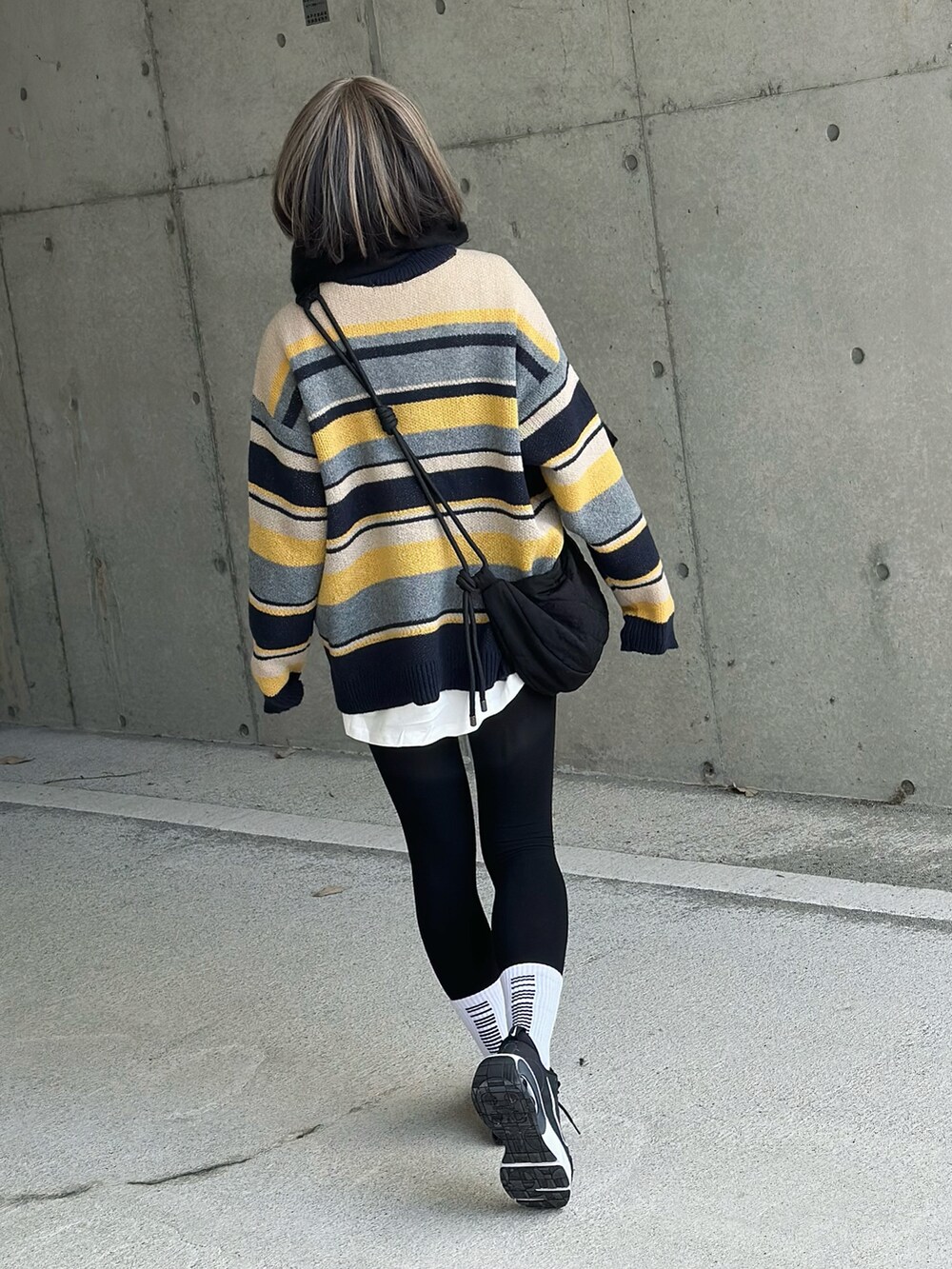 ブルー系のニット/セーター、ブラック系のショルダーバッグ、ブラック系のスニーカーを着用したレディースの冬コーディネートの4枚目の写真