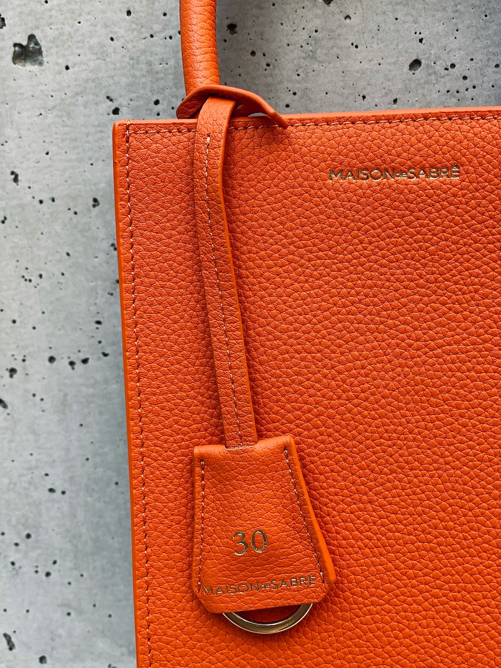 ホワイト系のベスト、ブラウン系のタンクトップ、オレンジ系のトートバッグを着用したレディースの夏コーディネートの3枚目の写真