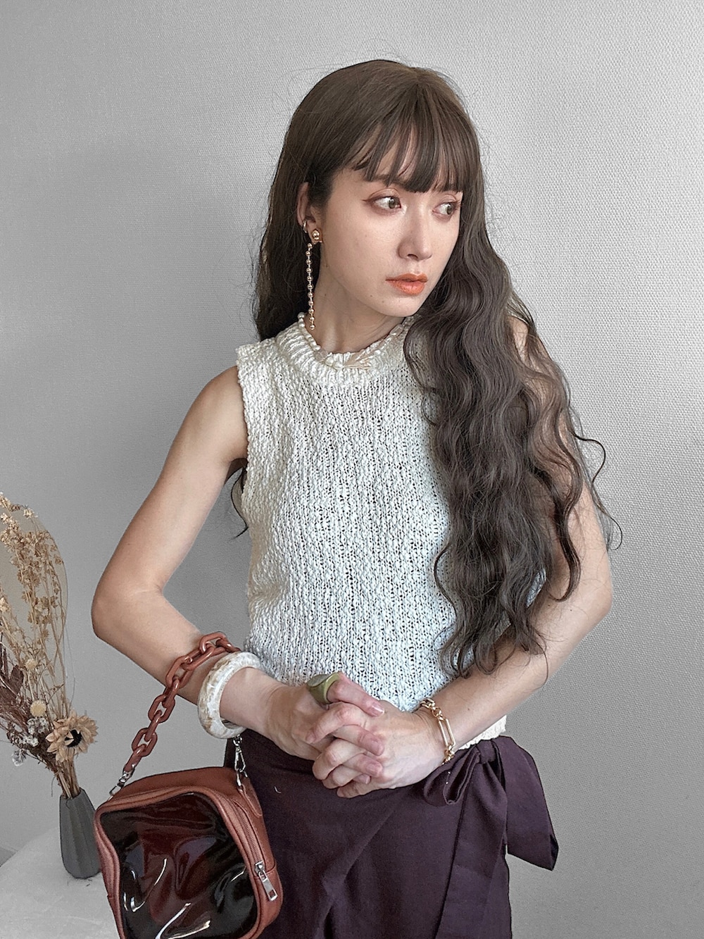 ホワイト系のベスト、ブラウン系のその他パンツ、ブラウン系のショルダーバッグを着用したレディースの夏コーディネートの2枚目の写真