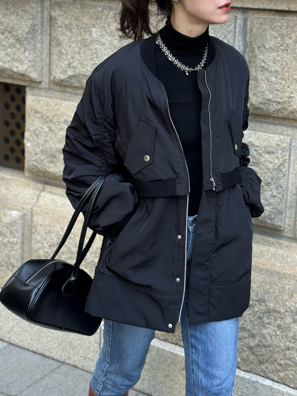 ブラック系のブルゾン、レッド系のブーツ、ブラック系のボストンバッグを着用したレディースの秋コーディネートの2枚目の写真