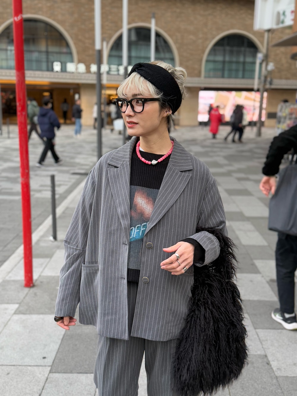 グレー系のセットアップ、ブラック系のニット/セーター、ブラック系のトートバッグを着用したレディースの冬コーディネートの2枚目の写真